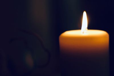 Close-up of lit candle in darkroom