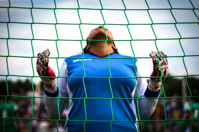 Low angle view of woman seen through net at soccer field
