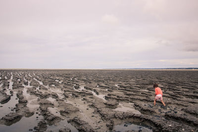 Woman walking on mud against sky