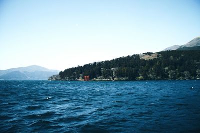 Scenic view of sea and mountains against clear blue sky