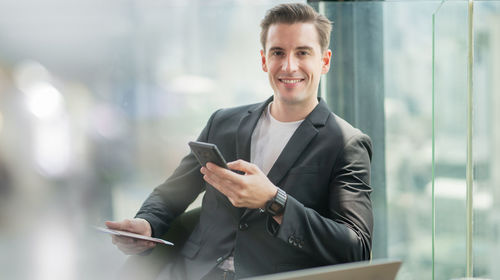 Portrait of smiling man standing on mobile phone