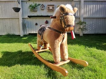 Rocking horse on grassy field against house in yard