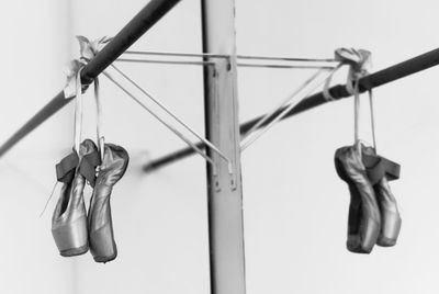 Low angle view of ballet shoes hanging on rod against clear sky