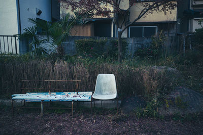 Empty chairs and tables in yard against building