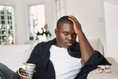 Young man looking away while sitting on table