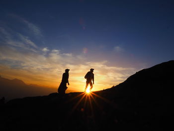 Silhouette man standing on mountain against sky during sunset