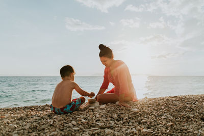 Mother and son stacking stones at beach