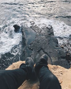 Low section of man standing on rock by sea