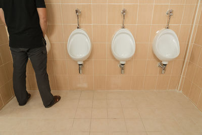 Low section of man urinating in public restroom