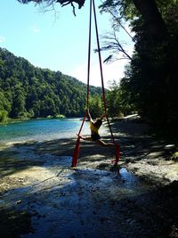 Man on swing at beach against sky