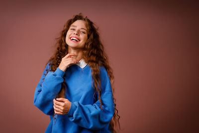 Portrait of young woman standing against gray background