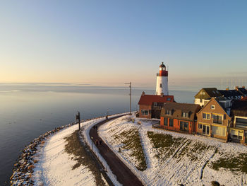 Buildings by sea against clear sky during sunset