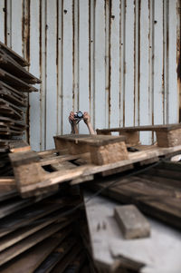 Cropped hands holding camera by wood