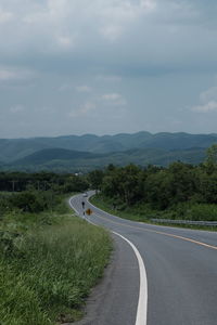 Road leading towards mountains against sky