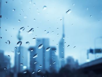 Close-up of wet window against sky