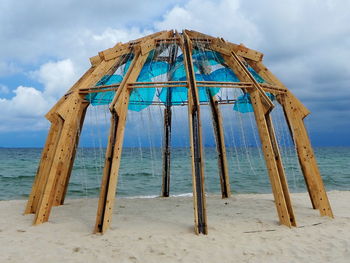 Wooden posts on beach against sky