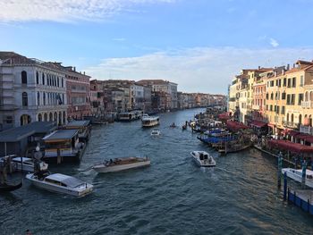 Boats moored on canal against buildings in city