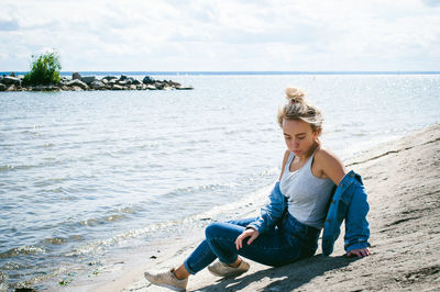 Full length of girl sitting on sand at beach