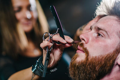 Close-up of woman shaving man beard