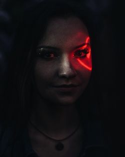 Red light falling on young woman eye in darkroom