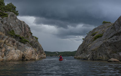 People on rock by sea against sky