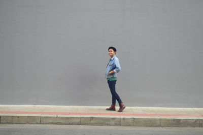 Full length of young man standing against wall