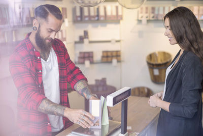 Owner weighing candies in front of customer in shop