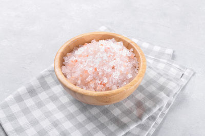 Pink himalayan salt in a wooden bowl on a light grey background, copy space