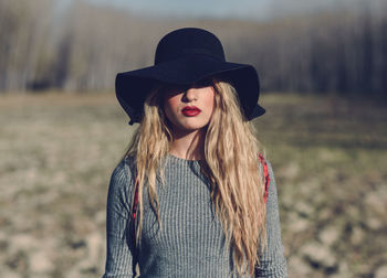 Young woman in hat standing on field