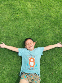 High angle view of smiling boy lying on grassy field