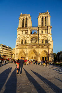 Group of people in front notre-dame  against blue sky