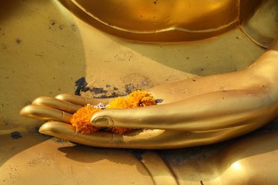 Orange marigolds on cropped gold buddha statue