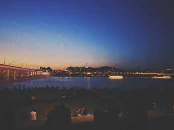 Illuminated city at waterfront during sunset