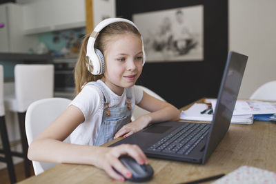 Smiling girl using laptop sitting at home