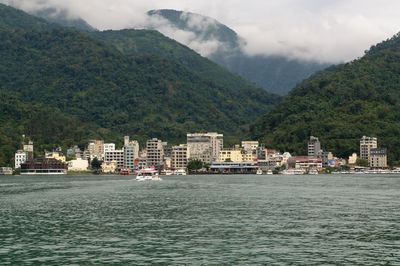 Sea by buildings in city against sky