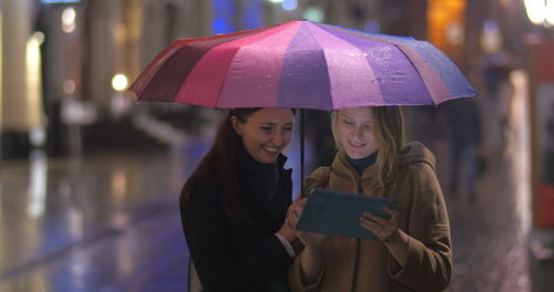 Woman holding umbrella while standing in city