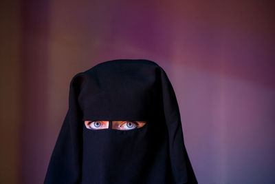 Portrait of woman wearing burka against wall