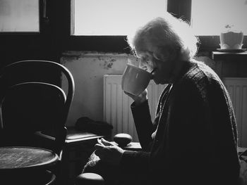 Side view of senior woman drinking coffee at home