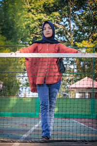 Portrait of girl standing against fence