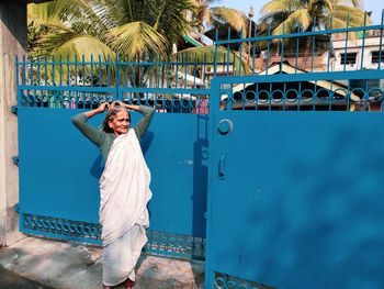 Full length of senior woman standing by gate outdoors