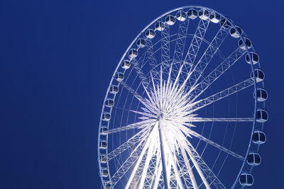 Low angle view of ferris wheel against blue sky