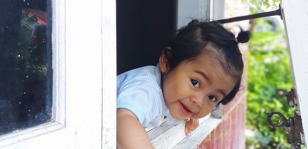 Portrait of cute girl looking through window