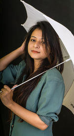 Portrait of smiling young woman standing in rain