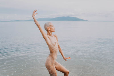 Rear view of woman jumping in sea against sky