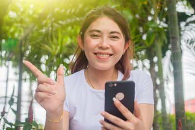 Portrait of smiling young woman using mobile phone outdoors