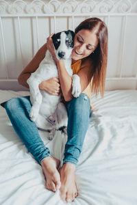 Full length of woman with dog on bed at home