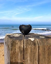 Close-up of wooden post on beach against sky