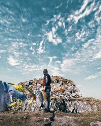 Rear view of man standing on rock against sky