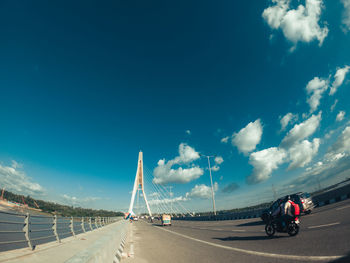 Vehicles on road against blue sky