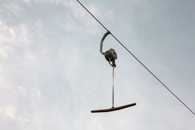 Low angle view of bird perching on rope against sky